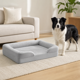 Medium dog standing beside the gray bolster dog bed for scale