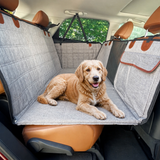 Dog resting in the gray rear-seat travel bed and cover